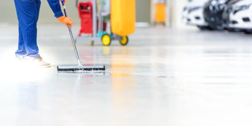 Is Your Flooring Showing Its Age? How Floor Care Can Revitalize Any Space; The car mechanic is cleaning, using a mop, rolling water from the epoxy floor. In the car service repair center